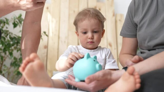 piggy bank. happy family a business concept. little son puts coins in piggy bank sits on the bed with parents. happy family collecting coins for home business plan. happy family hoarding save money