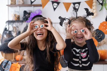 two diverse kids girl in costume of witch, having fun at home in kitchen, celebrating Halloween
