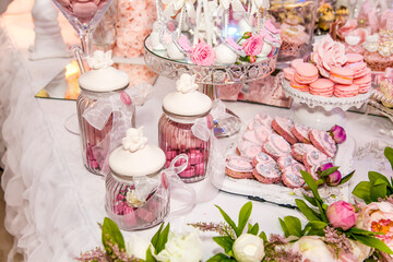 Delicious desserts at the wedding candy bar in the buffet area: cookies covered with icing, decorated with angels, cameo, sugar rosebuds and silver dye