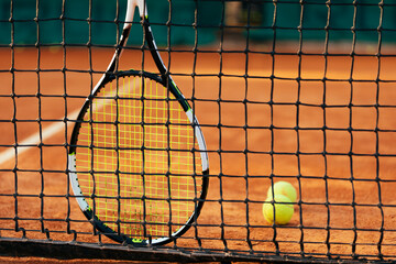Tennis racket and ball by net at at sports court