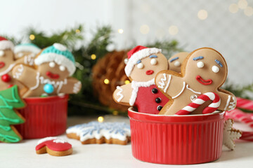 Delicious homemade Christmas cookies in bowl on white wooden table against blurred festive lights. Space for text