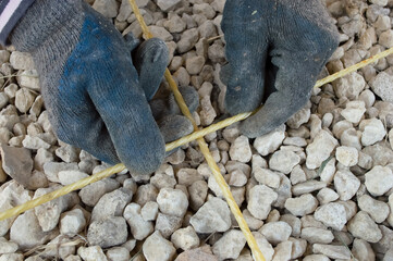 close-up - a worker's hands in gloves preparing fiberglass reinforcement for concrete work