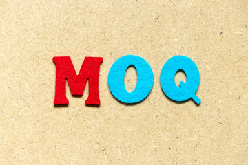 Color cloth alphabet letter in word MOQ (Abbreviation of Minimum Order Quantity) on wood background