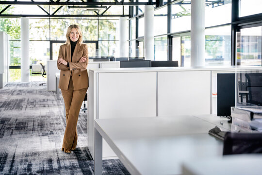 Confident female professional with arms crossed standing in office
