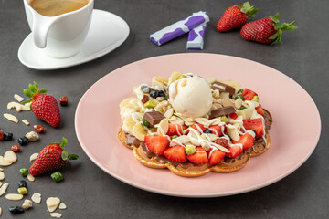 Heart waffle with banana and strawberry with gummy candy and ice cream on it.