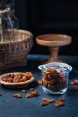 dried green raisins in wooden plate on black background