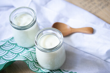 white yogurt in two glass jars on green background