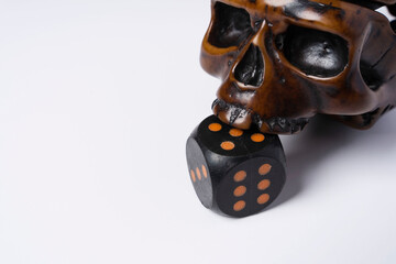 Creative composition of a skull and a dice, a skull bites a dice, on a white background, space for...