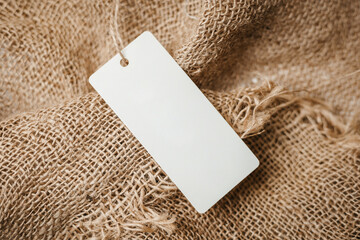 white empty label tag on vintage burlap background. Mockup