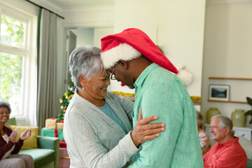 Happy diverse senior couple dancing in front of their diverse friends at christmas time