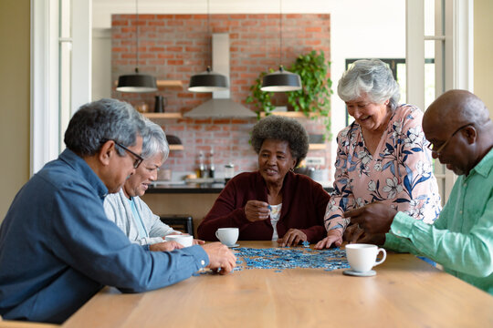 Group of diverse senior male and female friends doing puzzles at home