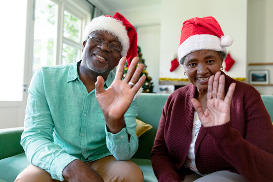 Happy african american senior couple wearing santa hats having video call at christmas time