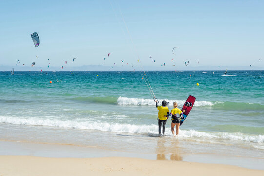 Female trainer with kiteboard instructing woman during sunny day
