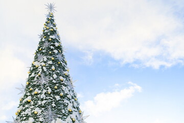 Christmas tree in a luminous garland. Christmas tree sprinkled with snow against the sky. snow...