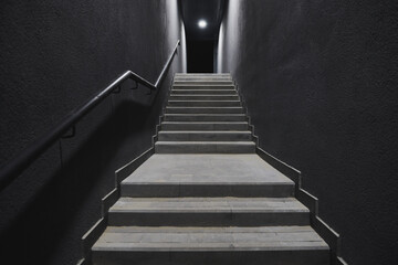 Stairs up from the underground. Grey walls with black handrail. New challenge concept photo. Dark...