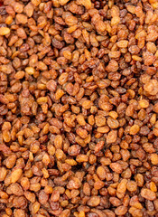 Dark grains of raisins (dried grapes) lie on the counter and form an abstract texture.