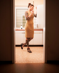 Tätowierte Frau steht am Kühlschrank, 70er Jahre Dress, Frau in der Küche