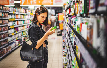 Young woman choosing care cosmetic in a supermarket. shopping