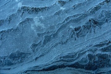 Natural rock texture of air and water eroded blue rock wall in a beach