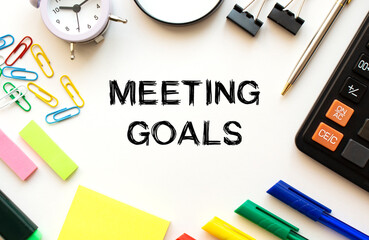 Office desk table with calculator, pens and other stationery. Text on the MEETING GOALS.