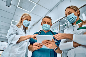 All research in a small gadget. Shot of three medical professionals talking using a digital tablet together at the hospital medical team.