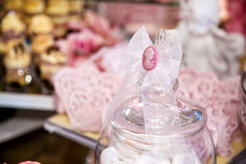 Delicious desserts at the wedding candy bar in the buffet area: a glass jar decorated with a bow and a cameo
