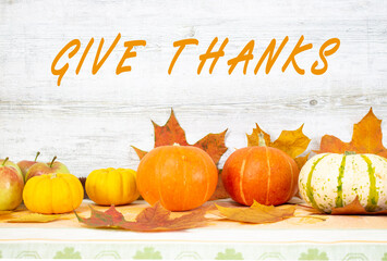 Give Thanks text handwritten. Thanksgiving day with fruits and vegetables on the table. Autumn harvest