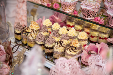 Delicious desserts at the wedding candy bar in the buffet area: glasses with layered dessert with chocolate, cream, nuts, souffle, whipped cream