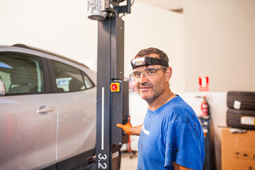 Content mechanic operating car elevator in workshop