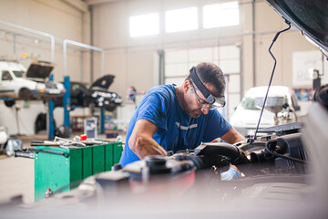 Male mechanic repairing automobile in workshop