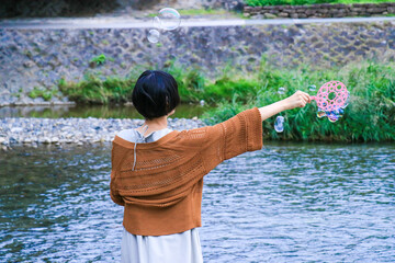 川沿いでシャボン玉を作るショートへアの女性