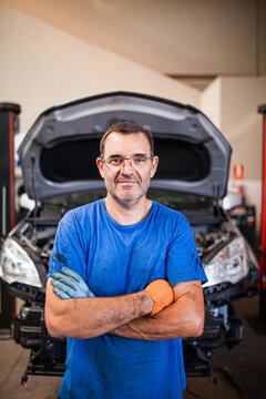 Cheerful mechanic against car in workshop