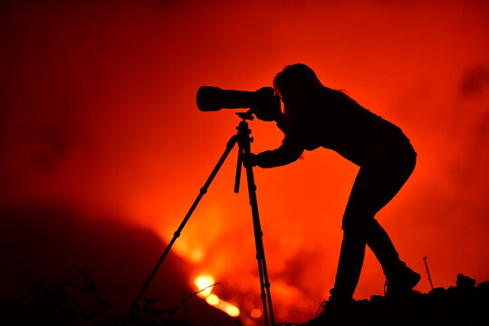 Fototapeta Woman silhouette of a photographer and in the background a lava explosion in La Palma Canary Islands 2021