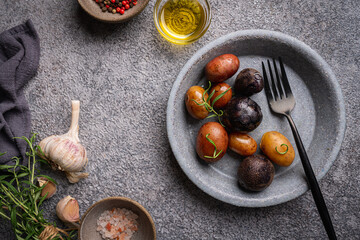 Various varieties of baked new colorful, white, red and purple potatoes on gray background, top view