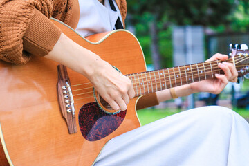 女の子がアコースティックギターを弾いている風景 - obrazy, fototapety, plakaty