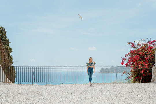 Stylish woman standing on roof of coastal house