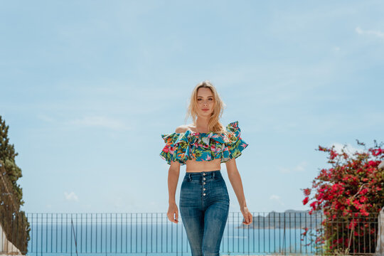 Stylish woman standing on roof of coastal house