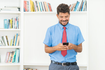 Happy businessman with beard sending message at mobile phone