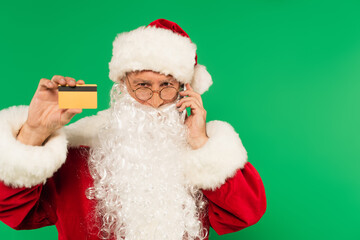 Santa claus talking on smartphone and holding credit card isolated on green