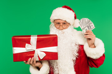 Santa claus holding gift box and cash isolated on green