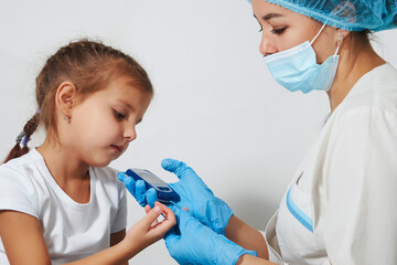 Young nurse doctor measuring blood sugar level of girl