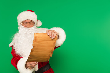 Santa claus in eyeglasses holding paper isolated on green