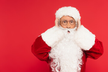 Amazed santa claus looking at camera isolated on red