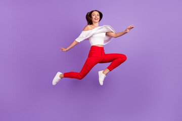Fototapeta na wymiar Photo of lovely cheerful lady jump enjoy flight go move wear white blouse pants isolated violet color background