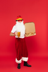 Father christmas in sunglasses holding mug of beer and pizza on red background