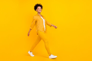 Fototapeta na wymiar Full size profile side photo of young lovely afro woman go step meeting isolated over yellow color background