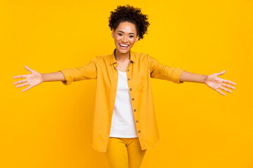 Photo of young cheerful african woman open arms glad embrace invite isolated over yellow color...