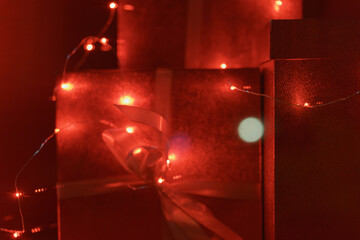 Photography of New Year shining gifts. Very bright red picture.  Gifts under the Christmas tree, home life. Festive concept. Beautiful background or template