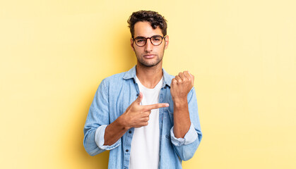 hispanic handsome man looking impatient and angry, pointing at watch