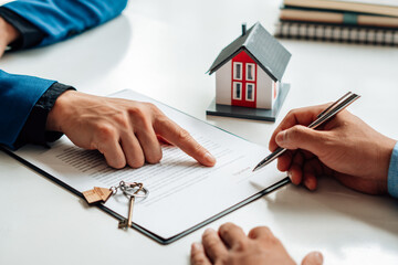 Customers interested in buying a home sign a signature to enter into a home purchase contract with a real estate agent. Mortgage loan approval home loan and insurance concept.